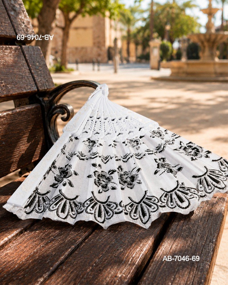 Abanico de mano con detalles de encaje y estampado floral en color negro sobre fondo blanco, con estructura perforada AB7046