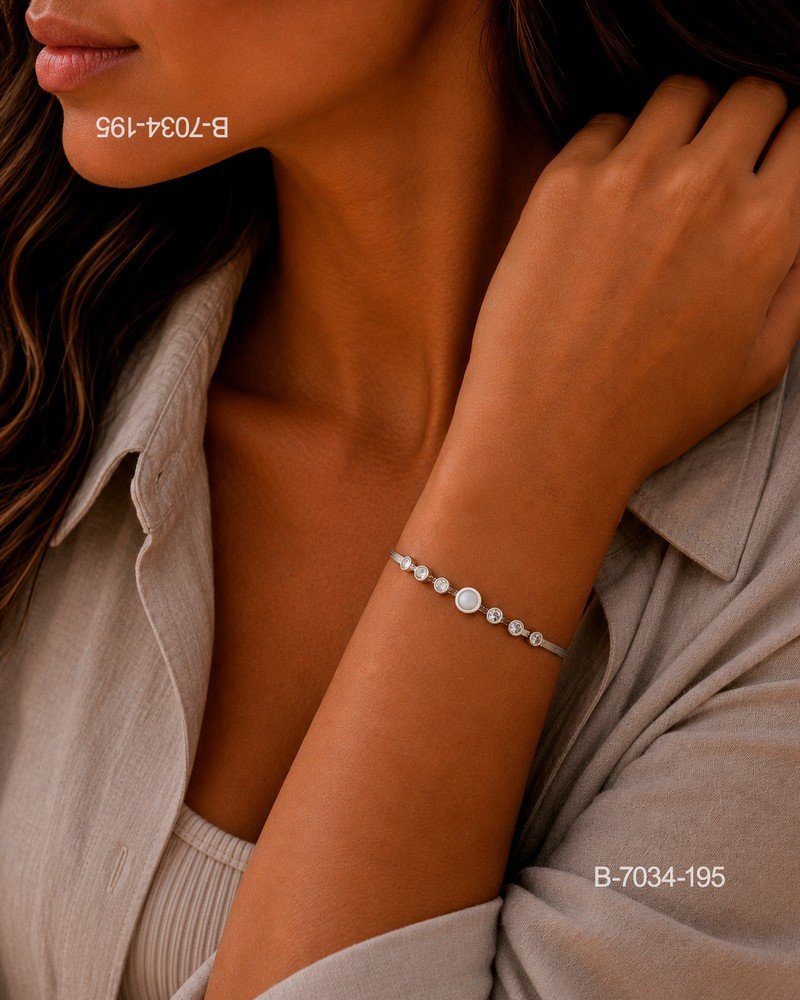 Pulsera de diseño elegante en color plateado o metalizado, compuesta por una cadena rígida o semi-rígida decorada con una secuencia de pequeños cristales y una piedra o perla central B7034